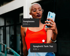Woman taking a selfie with a phone, wearing sunglasses and a spaghetti tank top, with product labels overlayed.